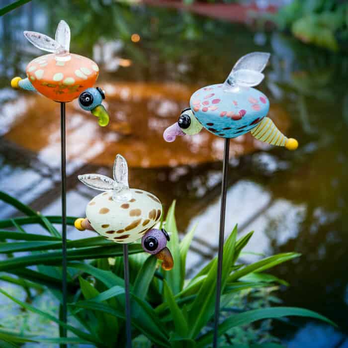 The LUCY glow worm made of mouth-blown glass decorates flower beds or garden ponds on a long metal rod.