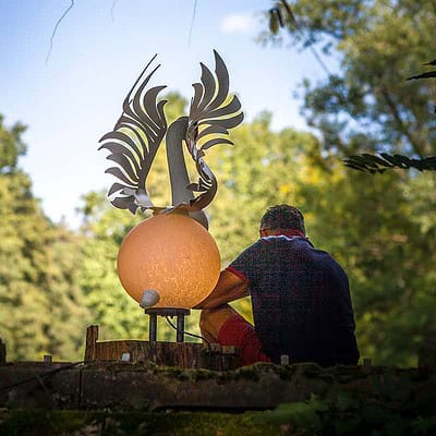 Ausruhen im Schatten: Glasobjekt Schwan HEKTOR und ein Besucher des Sommerfests